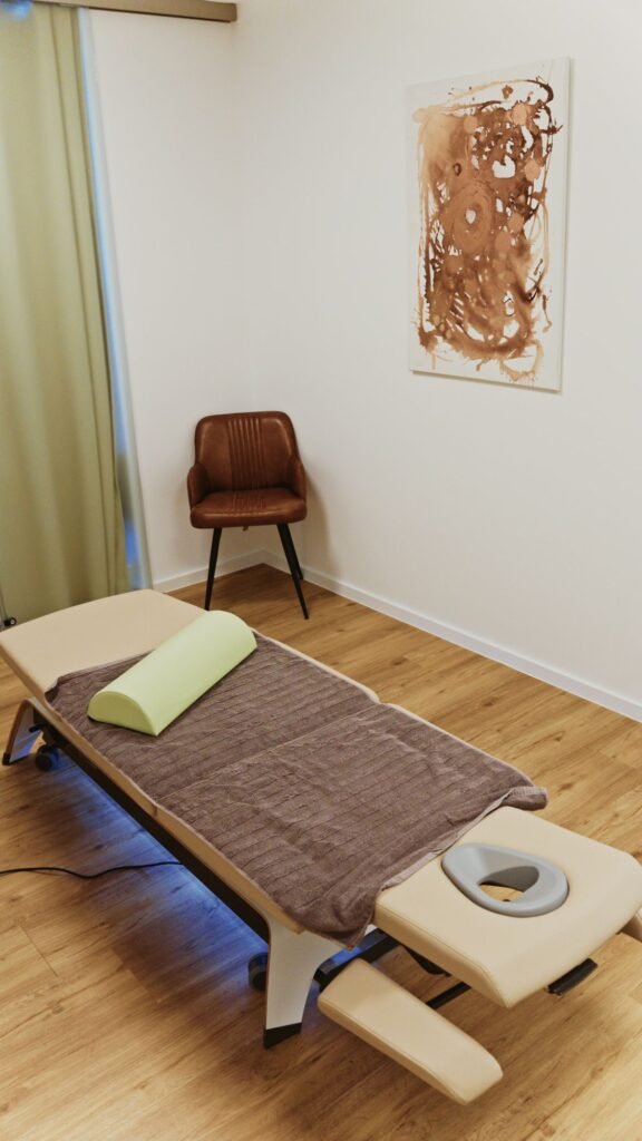 Behandlungsraum mit Therapieliege und Wandbild